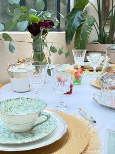 a table with plates and glasses and a vase with flowers at La Largarde in Six-Fours-les-Plages