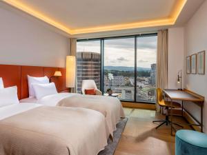 a hotel room with two beds and a desk and a window at Mövenpick Hotel Basel in Basel +154 photos