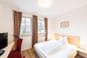 a bedroom with a bed and a desk and a television at Hotel Hanny Panoramic Views over Bolzano in Bolzano