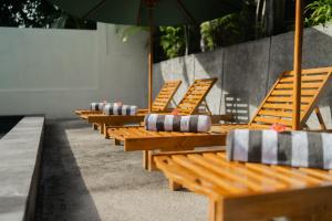 a row of wooden benches with an umbrella at Kamasan Nusa Penida By Reccoma in Nusa Penida