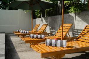 a row of wooden chairs with umbrellas at Kamasan Nusa Penida By Reccoma in Nusa Penida