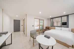 a bedroom with a large white bed and a living room at Rium Hotel in Mokpo
