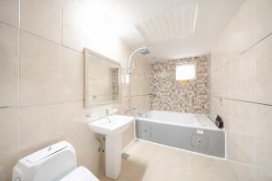 a bathroom with a tub and a sink and a toilet at Rium Hotel in Mokpo