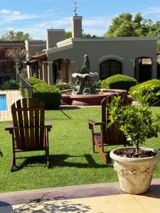 a couple of chairs and a fountain in a yard at Hotel Draghi in San Antonio de Areco
