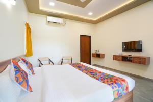 a bedroom with a white bed and a tv at FabHotel Nakshtra Resort in Tāsgaon