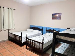 a bedroom with three beds in a room with blue walls at Villa Dona Jaca - Casa da Mata - Casa 02 in Socorro +42 photos