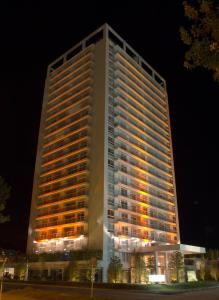 een hoog gebouw met 's nachts verlichting bij Yoo Apartamento - Rental Club in Punta del Este