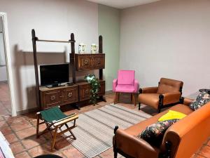 a living room with a couch and a tv and chairs at Villa Dona Jaca - Casa da Mata - Casa 02 in Socorro