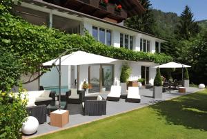a patio with chairs and umbrellas in front of a house at Gästehaus Tanneck mit Hallenbad in Reit im Winkl