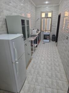 a kitchen with a white refrigerator and a tile floor at Khiran City in An Nāmī