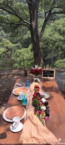 a long wooden table with plates and flowers on it at Glamping sin salir de la CDMX in Mexico City