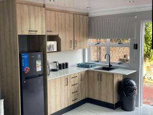 a kitchen with wooden cabinets and a black refrigerator at Abijah Ridgeview Studios in Roodepoort
