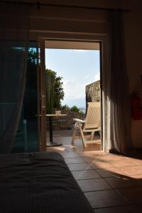 a bedroom with a door open to a patio with a chair at Olous Secret Hideaway - Sea View Studio Elounda in Elounda