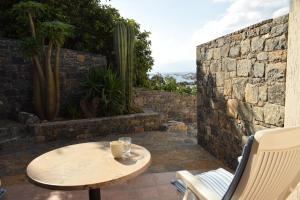 a table and chairs on a patio with a stone wall at Olous Secret Hideaway - Sea View Studio Elounda in Elounda
