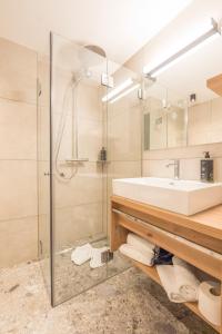 a bathroom with a glass shower and a sink at Hotel Kanisfluh in Mellau