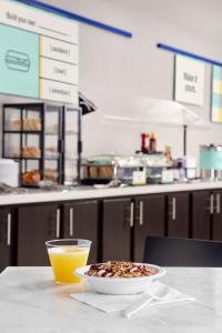 a bowl of cereal and a glass of orange juice on a table at Garner Hotel Frederick Southeast by IHG in Frederick +21 photos
