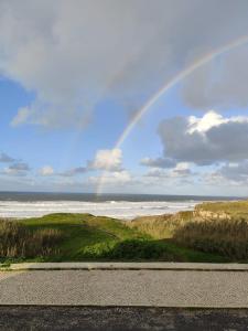 a rainbow in the sky over the ocean with a road at Gigi Beachfront in Ferrel