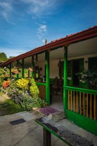 a green house with a porch with a bunch of bananas at Hostal y Camping Los Girasoles in Salento
