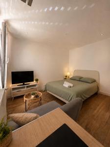 a living room with two beds and a television at Centre ville - Houilles A1 in Houilles