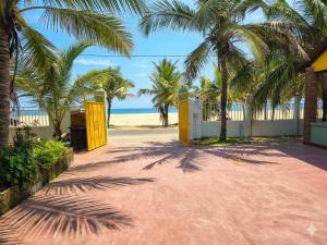 a beach with palm trees and a yellow gate at Beach Guest House Addalaichenai in Addalachenai
