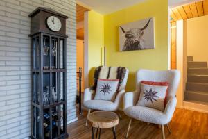 a living room with two chairs and a clock at Chalet Ravenstein in Fiesch
