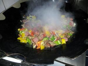 a wok filled with meat and vegetables with smoke at Chalé Vale do Ipê in Canelinha