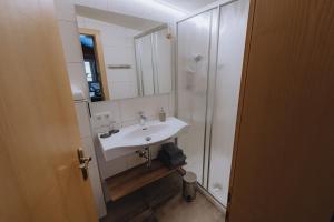 a bathroom with a sink and a shower with a mirror at Sonnenhang Montafon in Sankt Gallenkirch +53 photos