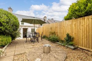 a patio with a table and an umbrella at Kite Cottage in Llangadwaladr