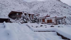 a house covered in snow in front of a mountain at Hotel de la Cañada Valle de Uco in Tunuyán