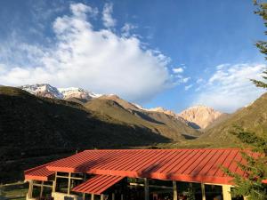 a building with a red roof with mountains in the background at Hotel de la Cañada Valle de Uco in Tunuyán