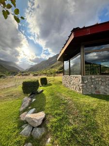 a stone building with a grass field and mountains in the background at Hotel de la Cañada Valle de Uco in Tunuyán