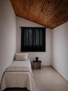 a bedroom with a bed and a black window at Chalé Luar da Serra in Camanducaia