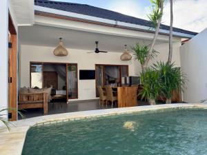 a villa with a swimming pool and a dining room at Ajolie Villa in Gili Islands