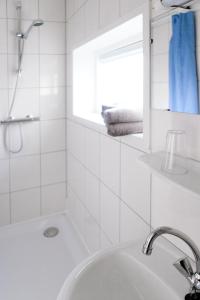 a white bathroom with a sink and a shower at HCR De Tukker in Westdorpe
