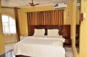a bedroom with a large bed with white sheets at Peace Vil in Kuto +1 photo