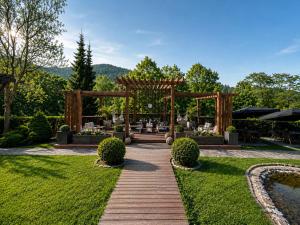 a garden with a wooden pergola and a pond at Parkhotel Luise Bad Herrenalb in Bad Herrenalb