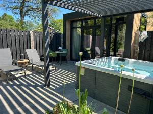a patio with a hot tub and a table at Wellnesslodge Merel jacuzzi sauna and privacy in Dalerveen
