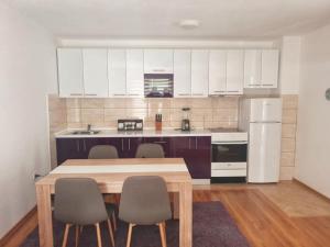 a kitchen with white cabinets and a wooden table and chairs at Villa Riverside Haven in Hadžići