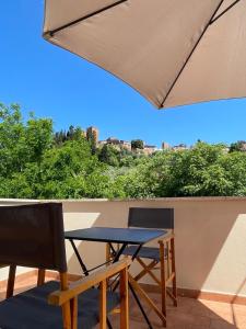 a table and chairs on a balcony with an umbrella at Appartamento ai piedi del Borgo in Certaldo