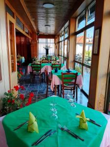 a restaurant with green tables and chairs and windows at Vittoria 1920 - hotel restaurant apartaments in Marzio