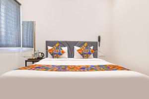 a bedroom with a large white bed with colorful pillows at FabHotel Trivana, Mahalaxmi Nagar in Indore +28 photos