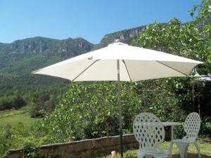 a white umbrella and two chairs under a table at Le Bel Coin in Ginoles