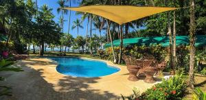 una piscina con sombrilla y sillas amarillas en Rafiki Beach Camp, en Matapalo