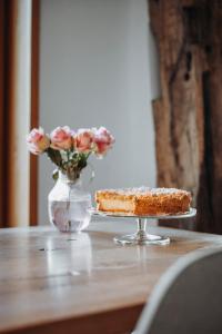 a piece of cake on a table with a vase of flowers at Josis Klause Café I Pension in Albstadt