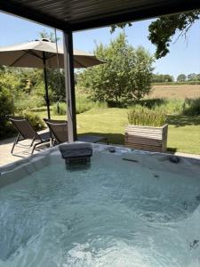 a hot tub with an umbrella and a table and chairs at Wellnesslodge Specht jacuzzi and sauna and privacy in Dalerveen