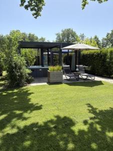 a gazebo with two chairs and an umbrella in a yard at Wellnesslodge Specht jacuzzi and sauna and privacy in Dalerveen