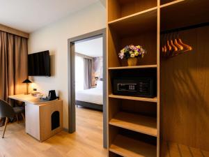 a hotel room with a desk and a bedroom at Mercure Alba Iulia in Alba Iulia