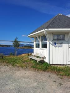 a white building with a bench in front of a lake at Kystbua 360 in Saltstraumen
