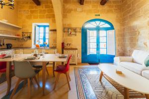a living room with a table and a blue door at Authentic Xagħra Farmhouse with Private Pool in Xagħra