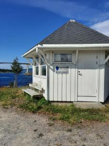 a small white building with a door and a window at Kystbua 360 in Saltstraumen